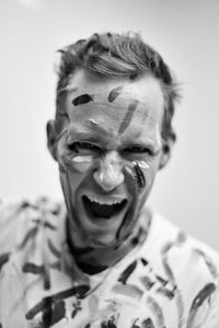 Close-up portrait of man with face paint screaming