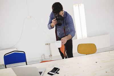 Blogger photographing coffee cup at desk in creative office