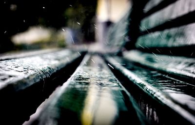 Close-up of raindrops on wooden bench