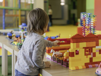 Toddler plays with toy blocks. boy stares on  toy constructor. interior of kindergarten or nursery. 