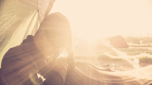 Portrait of young woman sitting on land against sunny day