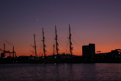 Silhouette sailboats by sea against romantic sky at sunset