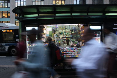 Business people rushing past a newsstand in new york city holding their phones 