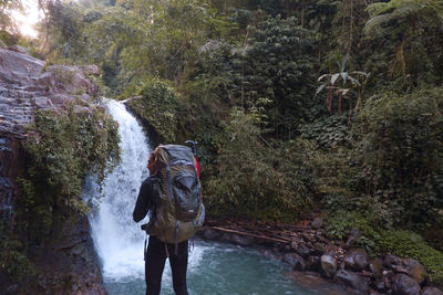 Gazing at the waterfall with a big backpack