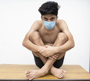 Portrait of young man sitting against white background