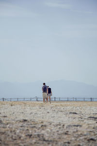 Rear view of people on beach against sky