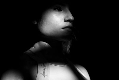 Close-up portrait of young woman against black background