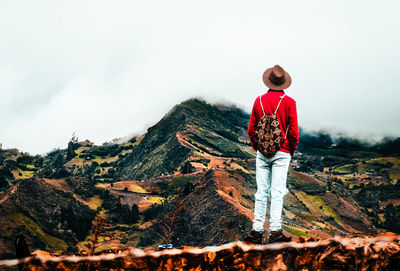 Rear view of man standing on mountain against sky