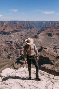 Full length of man standing on rock against sky