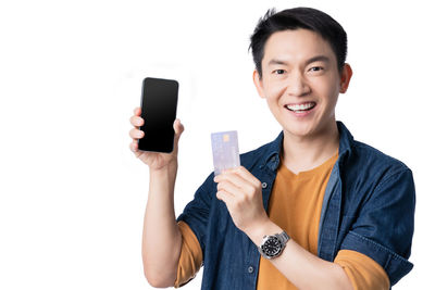 Portrait of smiling man holding camera against white background