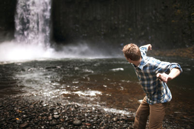 Rear view of man standing at waterfall