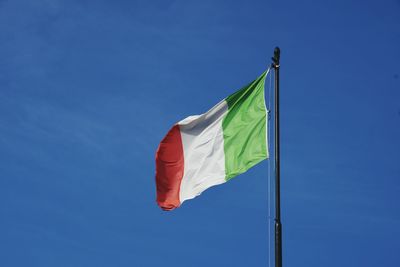Low angle view of flag against blue sky