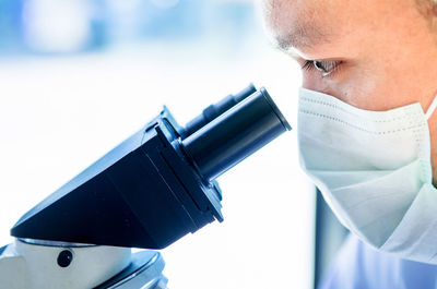 Close-up of scientist looking into microscope