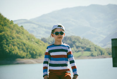 Boy sitting on railing against river