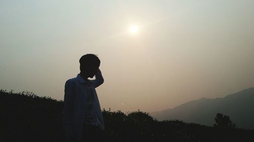 Man standing on mountain against sky during sunset