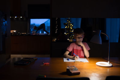 Boy writing in book at table