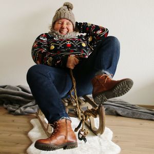 Full length of woman sitting on sled at home