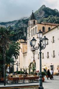 Sidewalk cafe by historic building against mountain