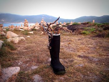 Black boot on land against mountains