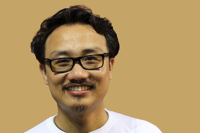 Portrait of young man wearing eyeglasses against gray background