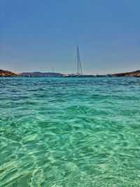 Sailboats in sea against clear blue sky