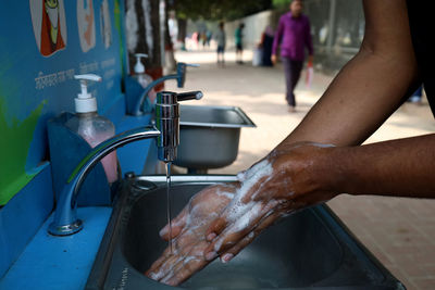 Midsection of man with faucet in water