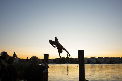 Silhouette people jumping against clear sky during sunset