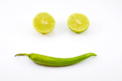 Anthropomorphic face made with halved limes and chili pepper on white background