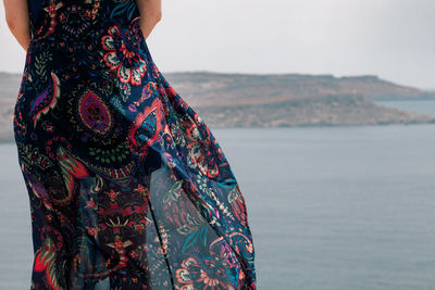 Midsection of woman standing on cliff against sea