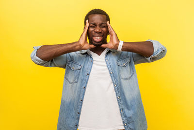 Portrait of smiling young man against yellow background