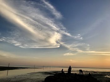 Silhouette people on beach against sky during sunset