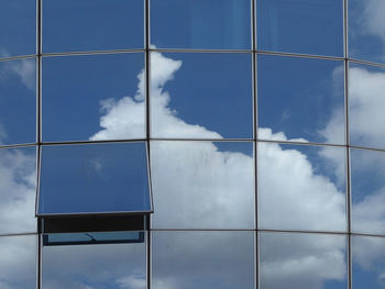 Low angle view of modern building with only one open window against blue sky