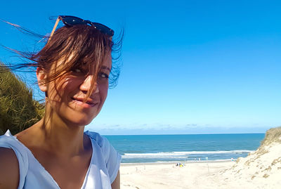 Close-up of young woman at beach against sky