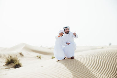 Man with arms outstretched against clear sky