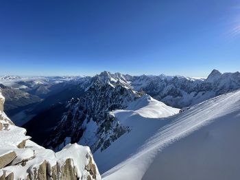 Scenic view of snowcapped mountains against clear blue sky