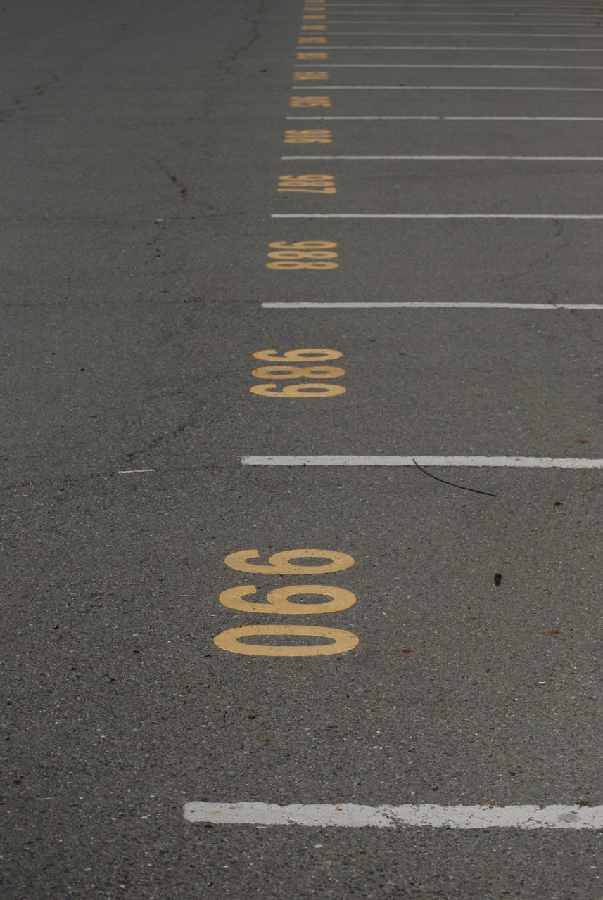 sign, symbol, road, road marking, communication, marking, high angle view, transportation, no people, day, text, yellow, city, asphalt, direction, street, outdoors, information, western script, the way forward, dividing line