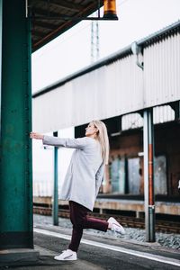 Side view of woman standing against building