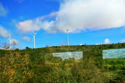 Windmills on field against sky