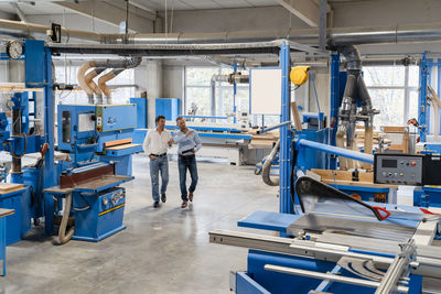 Two carpenters walking and talking in production hall