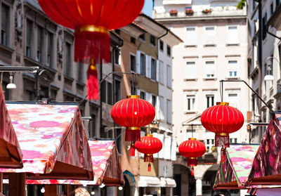 Red lanterns hanging on street amidst buildings in city