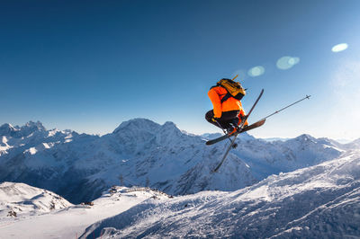 The skier jumps on the background of the blue sky and snow-capped mountains. freestyle skier