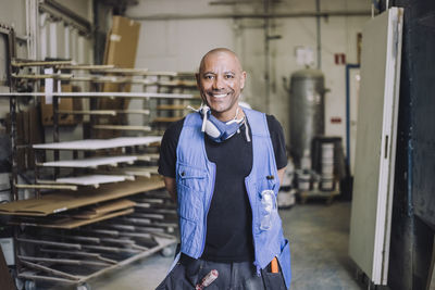 Portrait of smiling bald painter standing in workshop