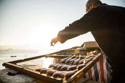 Rear view of man having food against sky