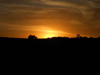 Scenic view of silhouette field against sky during sunset