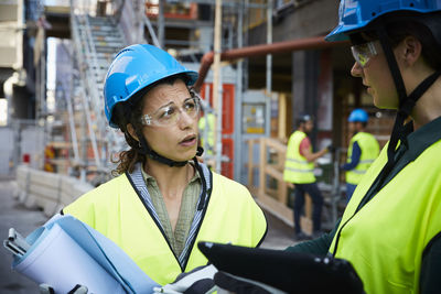 Female engineer discussing with coworker at construction site