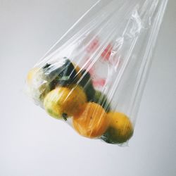 Close-up of fruits in plastic bag over white background