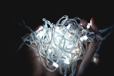 Close-up of hand holding decoration over black background