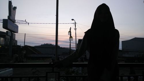 Silhouette man photographing city against sky during sunset