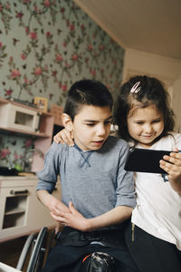 Sister showing video to autistic brother on smart phone at home