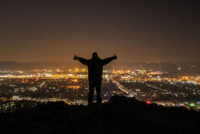 Silhouette of illuminated cityscape against sky at night